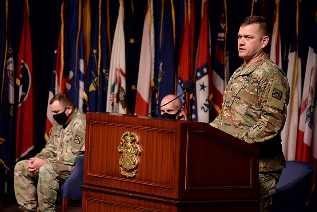 Incoming Special Troops Battalion Commander Lt. Col. Mark Winker delivers remarks as outgoing STB Commander Lt. Col. Charles D. Ausman, Combined Arms Center Chief of Staff Col. Thomas Bolen, and audience members present and watching via Facebook...