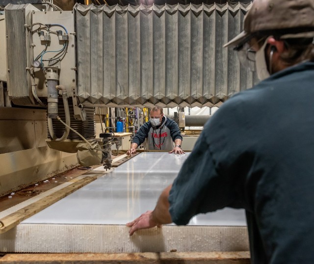 Machinist Leader Jason Golomb, foreground, and Engineering Technician (Mechanical) Robert VanBrunt position a piece of Plexiglas on the Flow water jet cutting machine to cut parts for the intubation cubes.