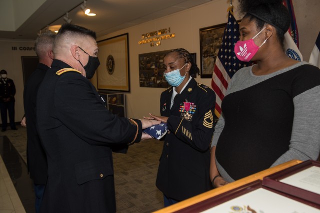 Master Sgt. Lashawnda Cole, receives an American flag during the Phantom Honors ceremony Oct. 30.  Cole retired after 20 years of honorable service as the logistics noncommissioned officer-in-charge for Headquarters and Headquarters Company, 13th Expeditionary Sustainment Command.
