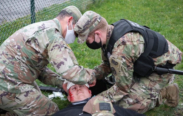Soldiers assigned to the 29th Military Police Company, Maryland Army National Guard, and the 566th Area Support Medical Company, 61st Medical Battalion, apply gauze to a head wound on a mock patient during a mass casualty training event at the...