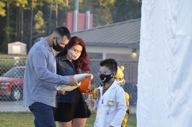 Staff Sgt. Freddie Aguiar, drill sergeant with 2nd Battalion, 13th Infantry Regiment read a riddle with wife, Tania and sons, Ian and Ethan during the 2020 Fall Festival and Movie Night Oct. 30. “Families and children have expressed how happy...