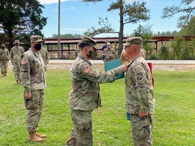 Col. Eric Flesch, 165th Infantry Brigade commander, pins the Army Commendation Medal on Staff Sgt. Bradly Urban for helping extinguish a fire in a neighbor’s quarters. Urban received the medal for his ‘outstanding service while going above...