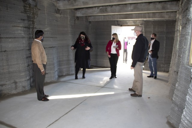 U.S. Army Engineer Research and Development Center (ERDC), Construction Engineering Research Laboratory (CERL), mechanical engineer and project lead for the Additive Construction Program and 3D Printing Megan Kreiger briefs the Principal Deputy Assistant Secretary of the Army for Installations, Energy and Environment Bryan Gossage from inside the 3D printed Barracks Hut at the ERDC, Forward Operating Base-Laboratory in Champaign, Ill., Oct. 30, 2020. The unique shape of the 3D printed walls and ceiling in the hut can withstand blasts/pressure, is stronger and can support more weight than conventional-type structures. The 3D printed concrete B-Hut reduces work hours, is more cost effective and saves valuable resources. (U.S. Army Corps of Engineers photo)