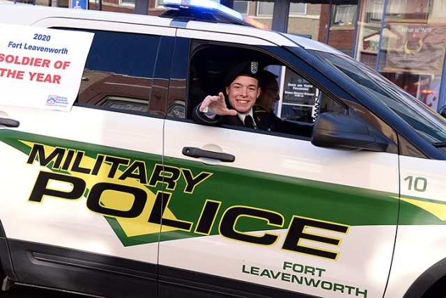 Combined Arms Center Soldier of the Year Spc. Thomas Snell, Headquarters and Headquarters Company, Joint Regional Correctional Facility, waves at spectators as he is driven along the Leavenworth County Veterans Day Parade route by Fort Leavenworth...