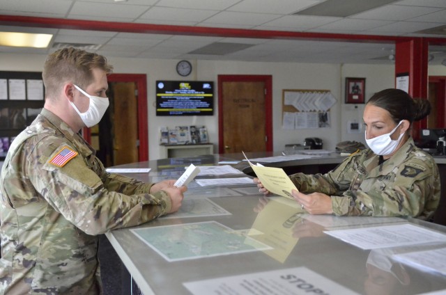 Sergeant First Class Desiree Murphy, master resiliency training instructor at the 1st Lt. J. Robert Kalsu Replacement Company, helps in-process Spc. Cody Vaughn into the 101st Airborne Divi-sion (Air Assault). Kalsu Soldiers and staff now wear personal protective equipment, such as face masks and maintain social distancing.