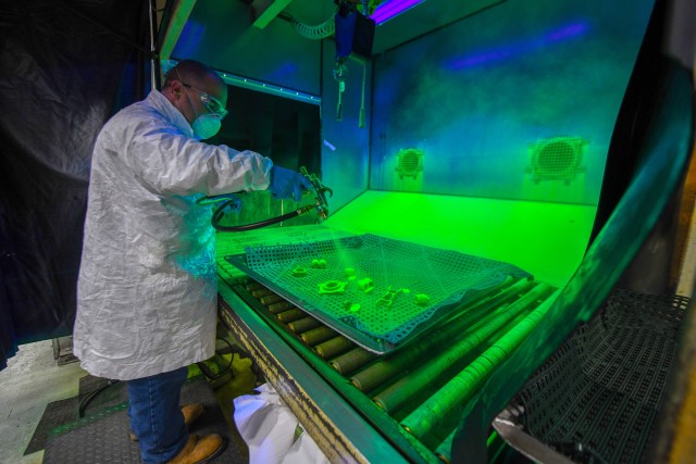 CCAD artisan Paul Zaklukiewicz, Non-Destructive Tester applies a concentrated fluorescent oil penetrant to the aircraft component to help detect defects under black light.