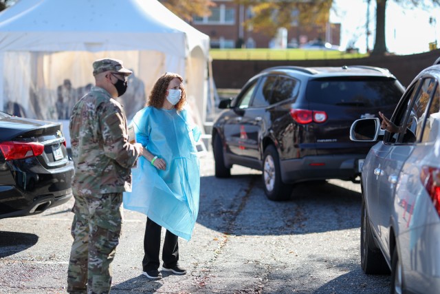 Tech. Sgt. Tony Wyatt, assigned to the North Carolina Air National Guard’s 263rd Combat Communications Squadron, left, and Burneta Barley, a registered nurse with Rhino Medical Services, talk to a patient in line at a drive-thru COVID-19 test site in High Point, North Carolina on Nov. 13, 2020. More than 170 North Carolina National Guard Soldiers and Airmen are activated across the state to support N.C. Emergency Management’s response to the pandemic. (U.S. Army Photo by Staff Sgt. Mary Junell)