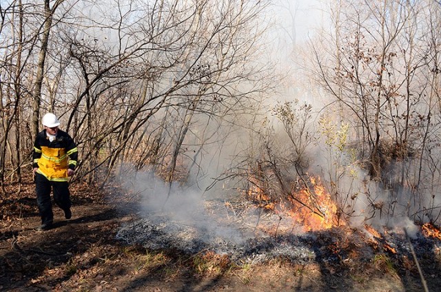 Fort Leavenworth Fire and Emergency Services Battalion Chief Dustin Hensley walks by a prescribed burn in progress off a multi-use trail near Sheridan Drive Nov. 17. "Pocket prairies" along the trail were identified several years ago in a...