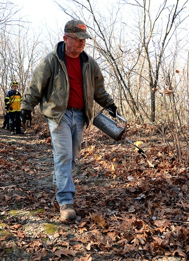 Scott Morrow, heavy equipment operator with the Directorate of Public Works, uses a drip torch to light the perimeter of a small prescribed burn Nov. 17 on a trail off Sheridan Drive. DPW personnel attended a prescribed burn workshop with the Fort...