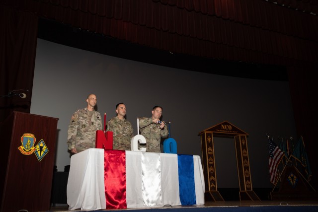 First sergeants from Headquarters, Headquarters Battalion, each light a candle as the officiant reads the meaning of the NCO creed during the NCO induction ceremony Nov. 10.