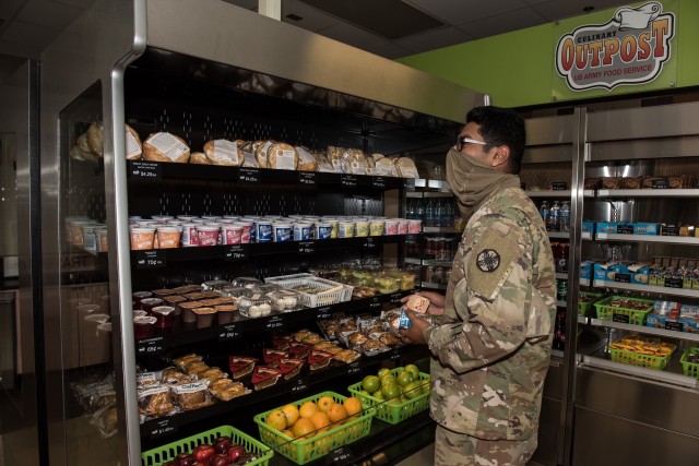 Spc. Christian Navarro, 553rd Field Feeding Company, examines his choices during the grand opening of the Culinary Outpost Kiosk Nov. 13.  As Soldiers gravitated towards different, more convenient, off-post food choices, the kiosks were created to offer Soldiers similar convenience store items on-post such as packaged fresh foods, fruits and beverages.
