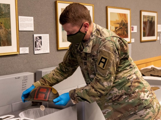 Kevin Braafladt, First Army Support Command historian, inspects a helmet worn by a First Army Soldier during World War I. A collection of artifacts will be loaned to First Army and displayed in the headquarters building once storage cases that allow for proper climate conditions are installed.