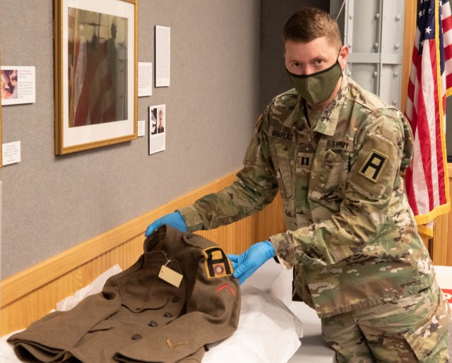 Kevin Braafladt, First Army Support Command historian, carefully handles a uniform worn by a First Army Soldier during World War I. A collection of artifacts will be loaned to First Army and displayed in the headquarters building once storage cases that allow for proper climate conditions are installed.