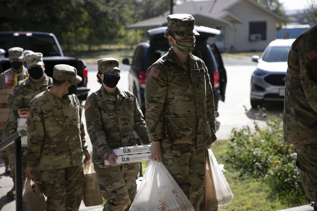 Soldiers with 504th Expeditionary Military Intelligence Brigade wait in line with nonperishable food items, Nov. 20, 2020, Nolanville, Texas. Food items needed to be weighted prior to entering the church. (U.S. Army photo by Soc. Tyler Tanaka)