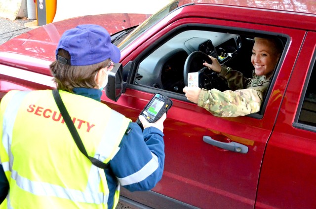 A Pond contracted security guard scans the Common Access Card (CAC) of a Soldier before allowing her to enter Rhine Ordnance Barracks in Kaiserslautern, Germany recently. If a CAC-holder is flagged in the Installation Access Control System. the screen on the scanner would show a red band instead of green.