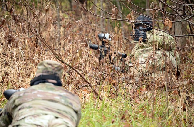 Spc. Gage Tomey, right, signals to his teammate Staff Sgt. Roque Ortega as the team makes its way toward the opposing force during the Headquarters and Headquarters Company, Joint Regional Correctional Facility's Best Watchdog Competition Nov. 23...