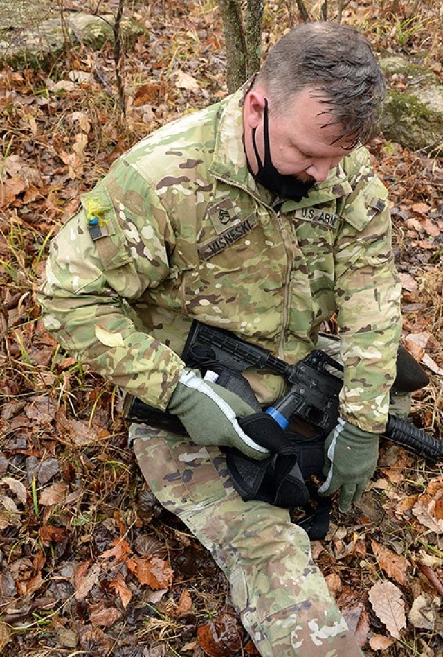 Staff Sgt. John Visneski, Headquarters and Headquarters Company, Joint Regional Correctional Facility, sits to the side of the trail after being hit with a paintball round by the opposing force during the Best Watchdog Competition Nov. 23 near the...