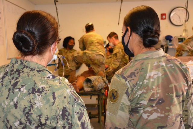Exercise facilitators watch as medical provider participants resuscitate a simulated patient in the clinical setting.