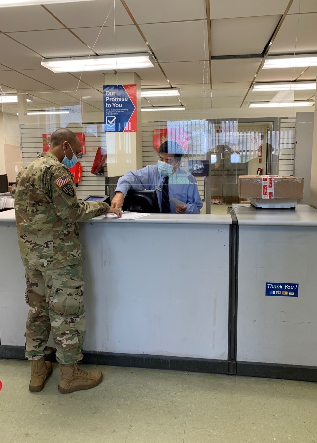 Tommy, from USPS, helps a service member mail a package during the post office’s reopening, Nov. 23, 2020. The post office closed in early January of this year for renovations in the building the office is located in.  