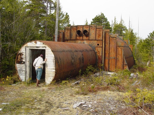 A community member peers into an abandoned military structure on Annette Island. Starting in 1940, the military and other federal agencies used the island for various purposes, leaving structures and debris behind as the land changed hands. The...