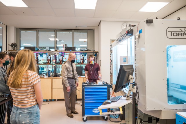 WIESBADEN, Germany-Tyler Houk, senior, explains to Brig. Gen. Jed Schaertl how students in classes and the robotics club use machine shop equipment to manufacture parts created on computer aided design (CAD) software.