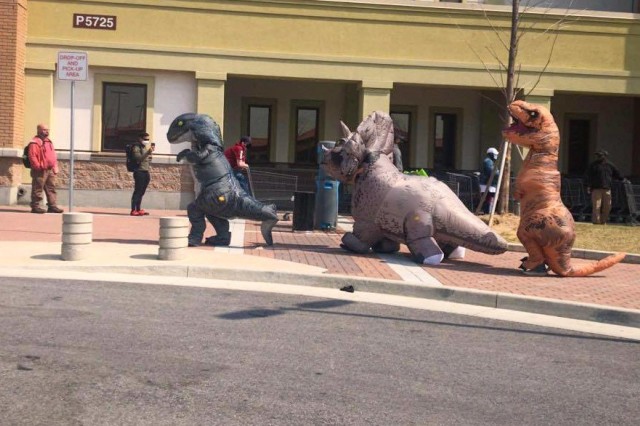CAMP HUMPHREYS, Republic of Korea - Young community members Sophia, Michael and Joe Hudak don their inflatable dinosaur costumes and help bring calm and merriment to community members in line at the Camp Humphreys commissary. Due to the...