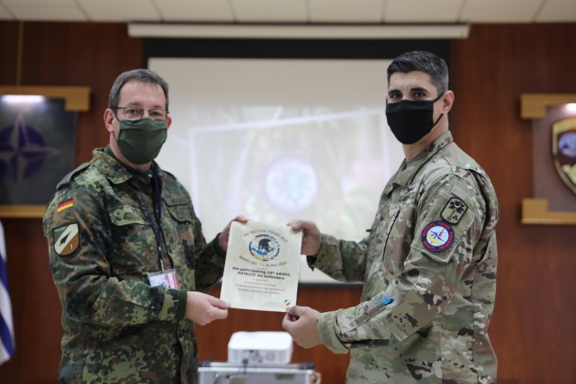 U.S. National Representative Maj. Richard Smothers, an air defense artillery fire control officer assigned to the 678th Air Defense Artillery Brigade, receives a certificate of appreciation on behalf of 10th AAMDC soldiers who participated in NAMFI 20 from Col. Andreas Noeske Commander of the German Air force AMD Wing 1, Nov. 26, 2020 here at the NATO Missile Firing Installation(NAMFI). NAMFI is a German led, Greece hosted installation and supported by The Netherlands. NAMFI has taken the COVID-19 risk into account and put forward strict guidance to combat the spread of the virus during the NAMFI 20 live fire. (U.S. Army photo by Sgt. Vincent Wilson)