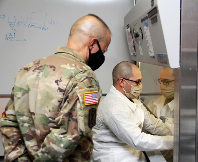 Spc. Darius Torres, of Littlefield, Texas, a medical laboratory technician assigned to Public Health Command-Pacific, demonstrates command’s new COVID-19 pooled testing procedures to Brig. Gen. Jack M. Davis, commanding general of Regional Health Command-Pacific, at PHC-P’s new COVID-19 Surveillance Testing Laboratory, Dec. 3, 2020. (U.S. Army photo by Christopher Larsen, RHC-P Public Affairs)