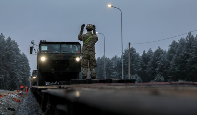 A Trooper assigned to 2nd Battalion, 8th Cavalry Regiment, 1st Armored Brigade Combat Team, 1st Cavalry Division, guides a HEMITT off a rail car near Padrade Training Area, Lithuania on Dec. 1, 2020. The weather conditions were freezing and cold,...