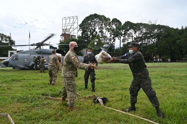 A Honduran Air Force Airman tosses a food bundle to a soldier assigned to Joint Task Force-Bravo at San Pedro Sula, Honduras, Nov. 23, 2020. At the request of the government of Honduras, Joint Task Force-Bravo is providing aerial support to relief operations in Honduras, impacted by Hurricane Iota. (U.S. Air Force Photo by Tech. Sgt. Jael Laborn)