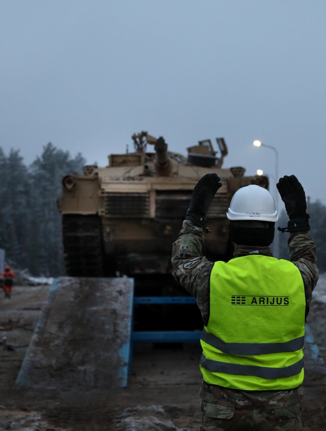 Sergeant Maj. Nathanael Green, operations sergeant major for 2nd Battalion, 8th Cavalry Regiment, 1st Armored Brigade Combat Team, 1st Cavalry Division, guides an M1 Abrams of a rail car Dec. 1, 2020, near the Pabrade Training Area, Lithuania. The...
