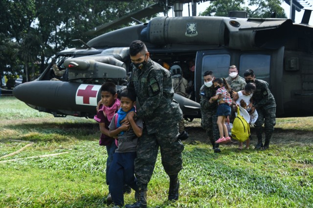 Joint Task Force-Bravo members and Honduran soldiers escort rescued Honduran family off of U.S. Army HH-60 Black Hawk helicopter at San Pedro Sula, Honduras, Nov. 13, 2020. JTF-Bravo's forward deployment to Honduras highlights the importance of cooperation and training with partners to build trust and teamwork. (U.S. Air Force photo by Staff Sgt. Elijaih Tiggs)