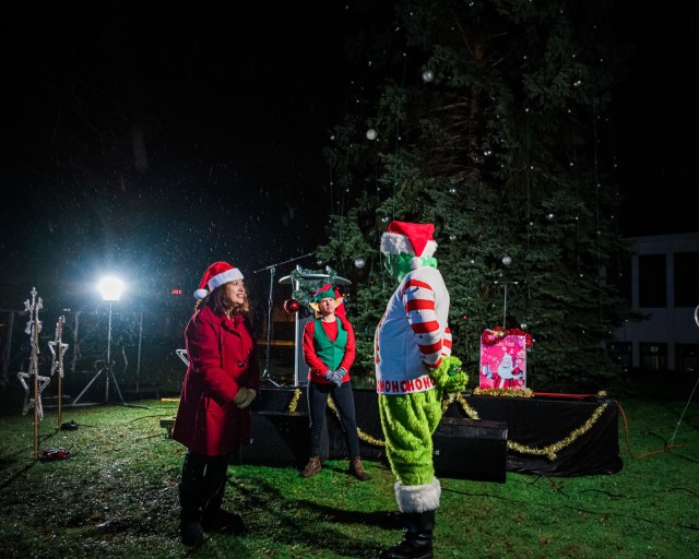 WIESBADEN, Germany -- In the rain, Jane Porto-Turner, Family and MWR sponsorship and advertising manager, an elf and the Grinch discuss holiday cheer as a part of the pre-ceremony live stream Dec. 4 on Clay Kaserne.