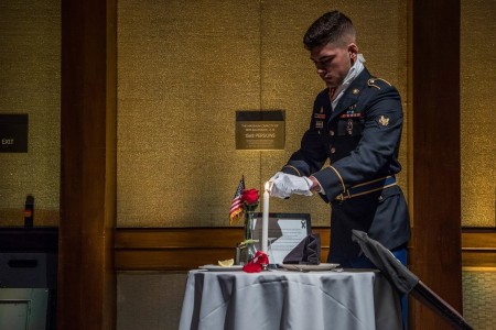 Spc. Brendon McCormick lights the candle at the Prisoner of War/Missing in Action table at Hilton Hawaiian Village, Hawaii, Jan. 16, 2020.