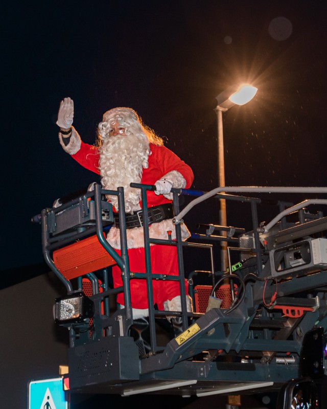 WIESBADEN, Germany -- Santa, on a firetruck, waves to children as Operation Santa's Flight progresses through Newman Village housing Dec. 4 on Clay Kaserne. Prior to a virtual tree-lighting ceremony, Santa toured each housing area to wave at the...