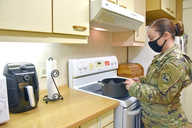 WIEBADEN, Germany - Staff Sgt. Joy Higgins, orderly room non-commissioned officer in charge, Headquarters and Headquarters Company, 66th Military Intelligence Brigade, prepares dinner in her apartment. Higgins recently moved from the barracks to...