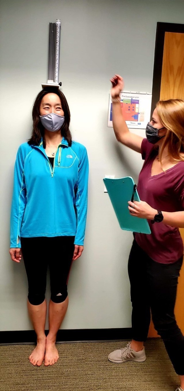 Fort Benning Army Wellness Center Health Educator McKenna Cornett measures the height of a patient.