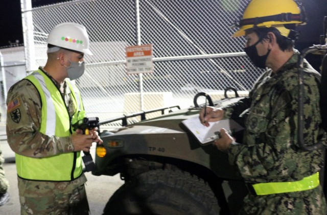 Sgt. 1st Class Jose Perez and Petty Officer 1st Class Snake Blocker take the military shipping label numbers off of a humvee as it exits the USNS Fisher on Dec. 5.