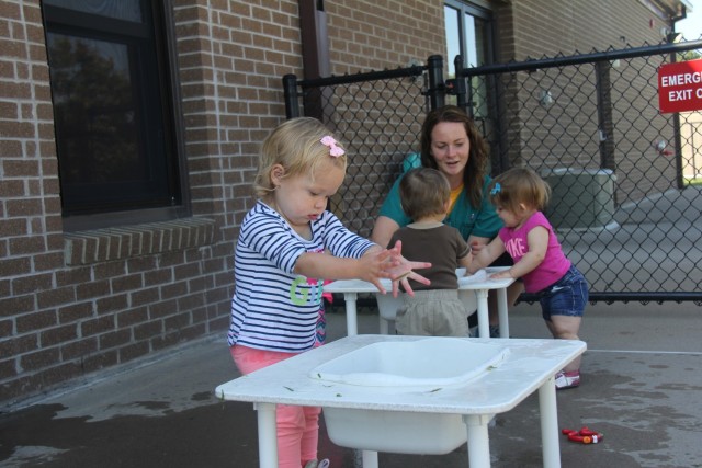 A student at the Child Development Center plays at a water table while Sierra Butzler, child and youth program assistant, helps other toddlers with a water activity Aug. 8, 2017, at Fort McCoy, Wis. The Fort McCoy CDC was recently reaccredited...