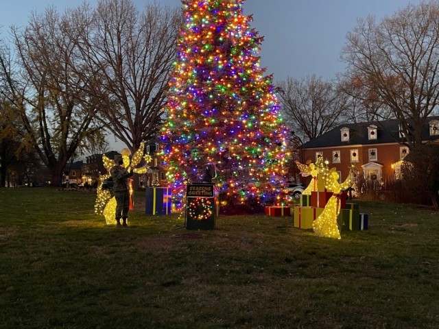 (Left) JBM-HH Commander Col. Kimberly Peeples looks at the joint base Christmas tree after (center) Imani Francis flipped the switch to light it Wednesday next to Bldg. 59, the joint base headquarters building.