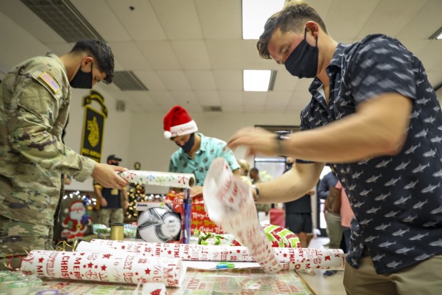 Soldiers and Families with 1st Battalion, 27th Infantry Regiment "Wolfhounds", 2nd Infantry Brigade Combat Team, 25th Infantry Division, wrap gifts to donate to the Holy Family Home orphanage on December 4, 2020 at Schofield Barracks, Hawaii. 1-27 IN and the Holy Family Home orphanage in Osaka, Japan, have an enduring relationship dating back to just after World War II, when Soldiers took up a collection for the orphanage during the holiday season in 1949. (U.S. Army photo by Staff Sgt. Thomas Calvert)