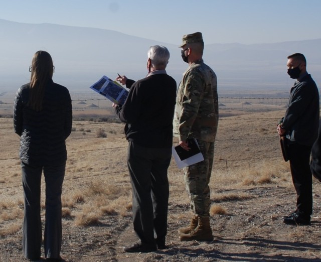 Civilians and soldier looking over high desert valley.