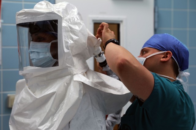 Maj. (Dr.) Neel Shah, an anesthesiologist at Landstuhl Regional Medical Center, gets assistance with putting on a powered air-purifying respirator.