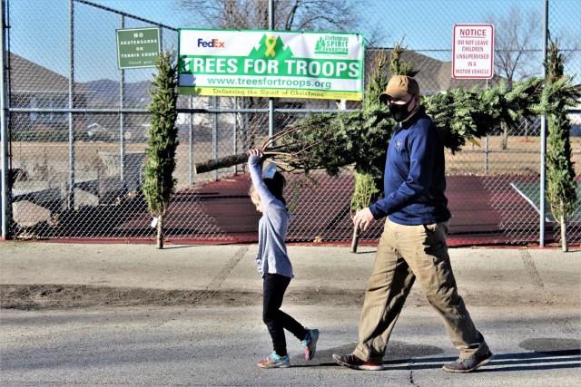 Military family members carry a tree Dec. 4, 2020, during the Trees for Troops event at the South Post Housing area at Fort McCoy, Wis. Eighty free Christmas trees were distributed to Fort McCoy military families thanks to the Trees for Troops organization. This was fifth consecutive year the trees were distributed. The Directorate of Public Works Housing Division coordinated the distribution. (U.S. Army Photo by Scott T. Sturkol, Public Affairs Office, Fort McCoy, Wis.)