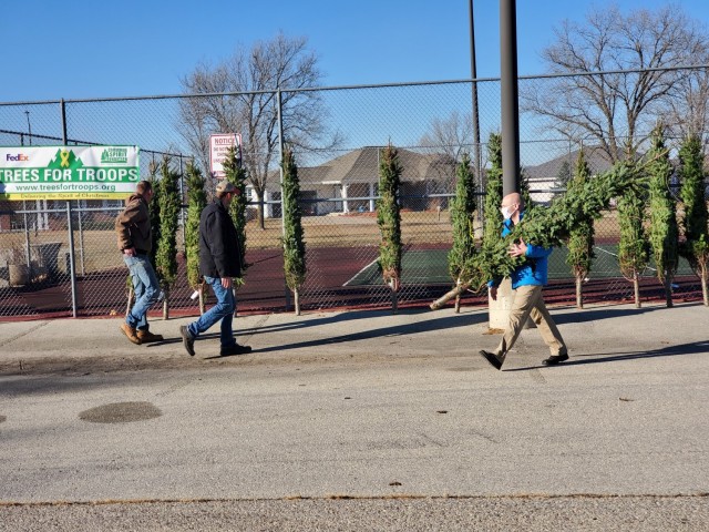Military family members carry a tree Dec. 4, 2020, during the Trees for Troops event at the South Post Housing area at Fort McCoy, Wis. Eighty free Christmas trees were distributed to Fort McCoy military families thanks to the Trees for Troops...