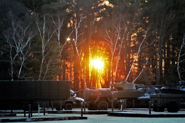 A frosty morning is slowly warmed with the rays of the sun glowing through the trees Dec. 10, 2020, at the Equipment Park in the historic Commemorative Area at Fort McCoy, Wis. Morning temperatures in the 20s caused widespread frost. (U.S. Army...