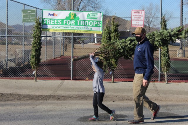 Military family members carry a tree Dec. 4, 2020, during the Trees for Troops event at the South Post Housing area at Fort McCoy, Wis. Eighty free Christmas trees were distributed to Fort McCoy military families thanks to the Trees for Troops...