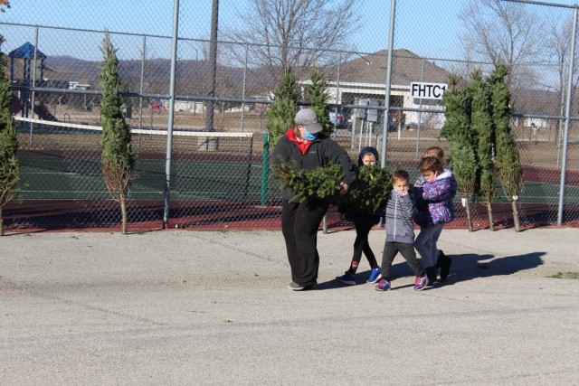 Military family members carry a tree Dec. 4, 2020, during the Trees for Troops event at the South Post Housing area at Fort McCoy, Wis. Eighty free Christmas trees were distributed to Fort McCoy military families thanks to the Trees for Troops...