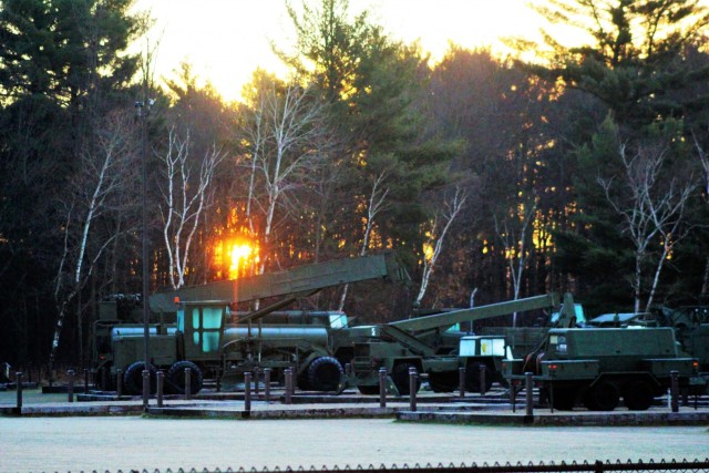 A frosty morning is slowly warmed with the rays of the sun glowing through the trees Dec. 10, 2020, at the Equipment Park in the historic Commemorative Area at Fort McCoy, Wis. Morning temperatures in the 20s caused widespread frost. (U.S. Army...