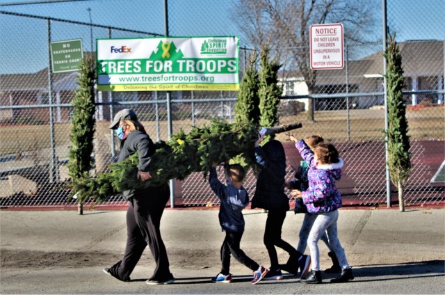Military family members carry a tree Dec. 4, 2020, during the Trees for Troops event at the South Post Housing area at Fort McCoy, Wis. Eighty free Christmas trees were distributed to Fort McCoy military families thanks to the Trees for Troops...